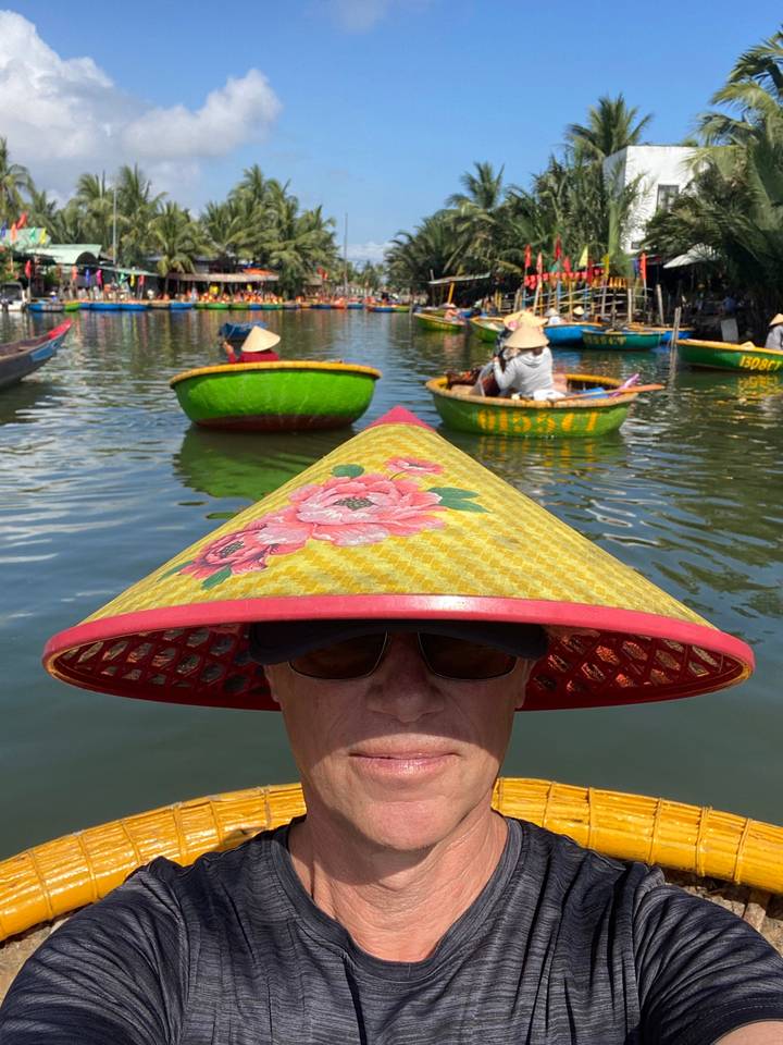 Personne avec des lunettes de soleil et un chapeau traditionnel sur l'eau.