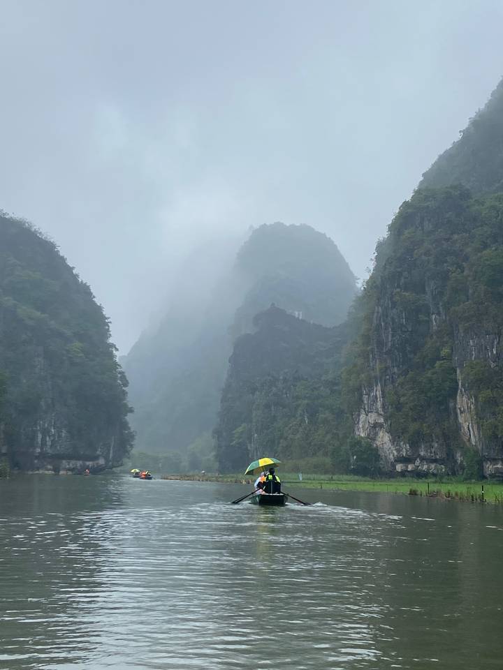 Bateaux sur une rivière brumeuse avec des karsts calcaires.