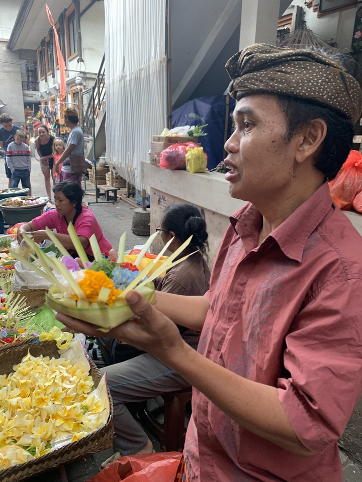 Person holding a flower offering at a market.
