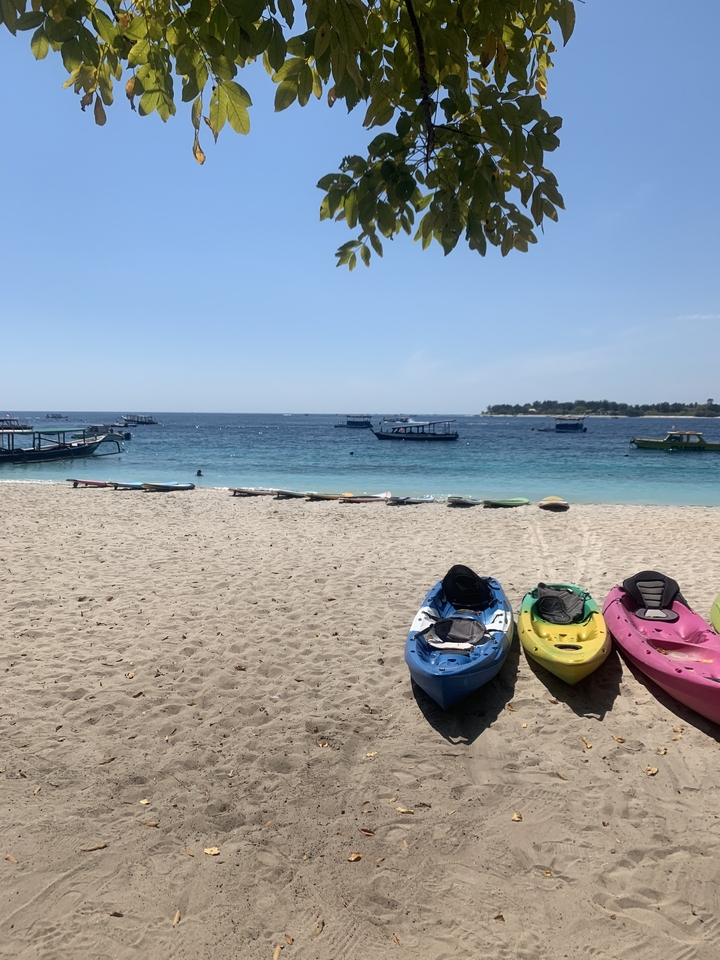 Kayaks and boats on a sandy beach with calm sea.