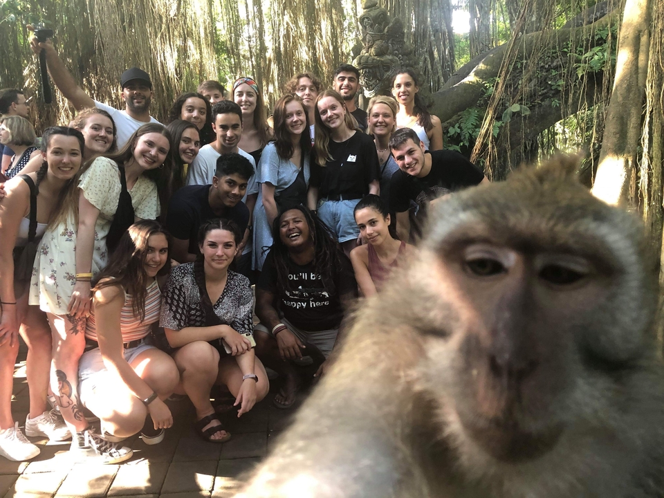 Large group of people with a monkey selfie in a tropical area.