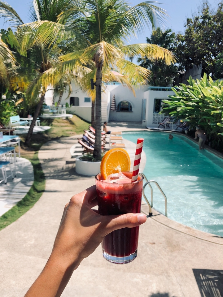 Refreshing drink held by the poolside with orange garnish.