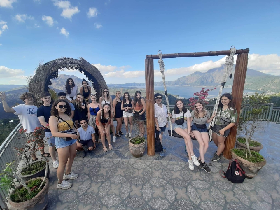 Large group posing with a scenic mountain view behind.