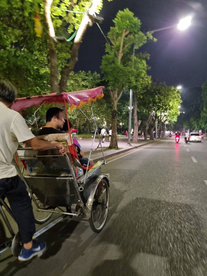 Person in a cyclo on a street at night.