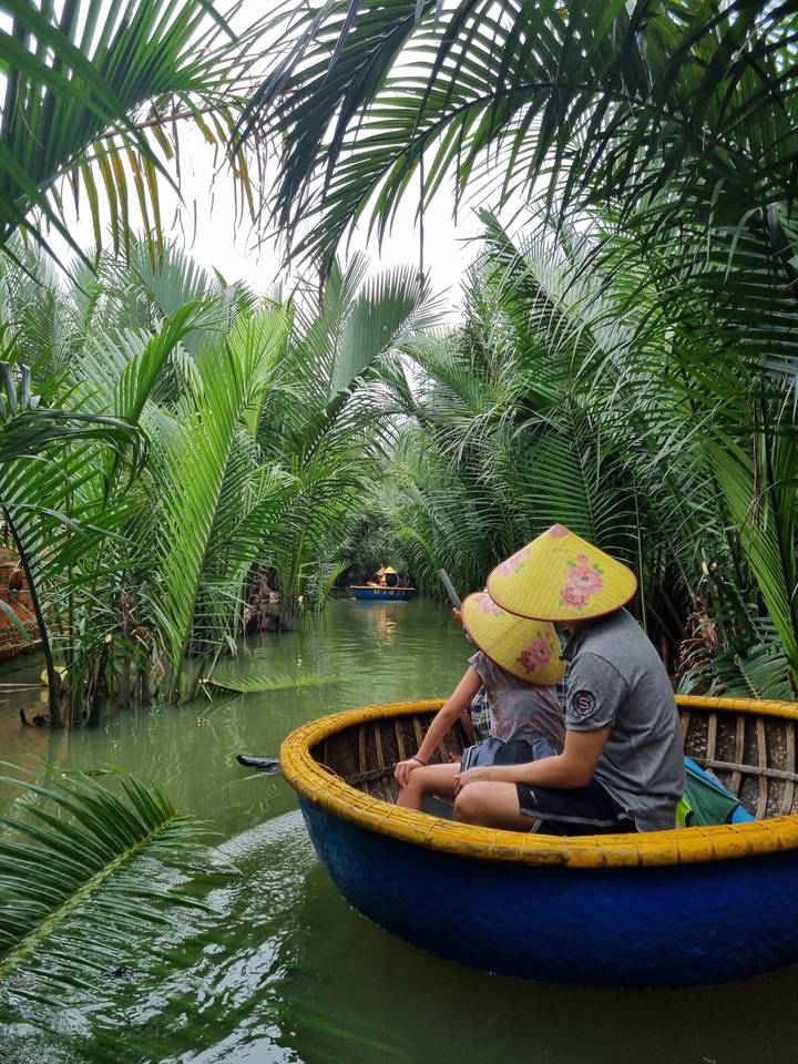 People paddling in a small boat through lush vegetation.