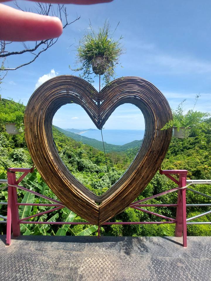 Heart-shaped wooden structure with a view of the sea.