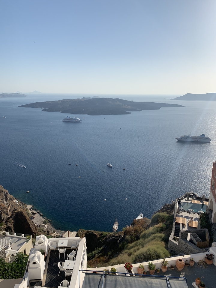 Wide view of the sea with cruise ships and islands.