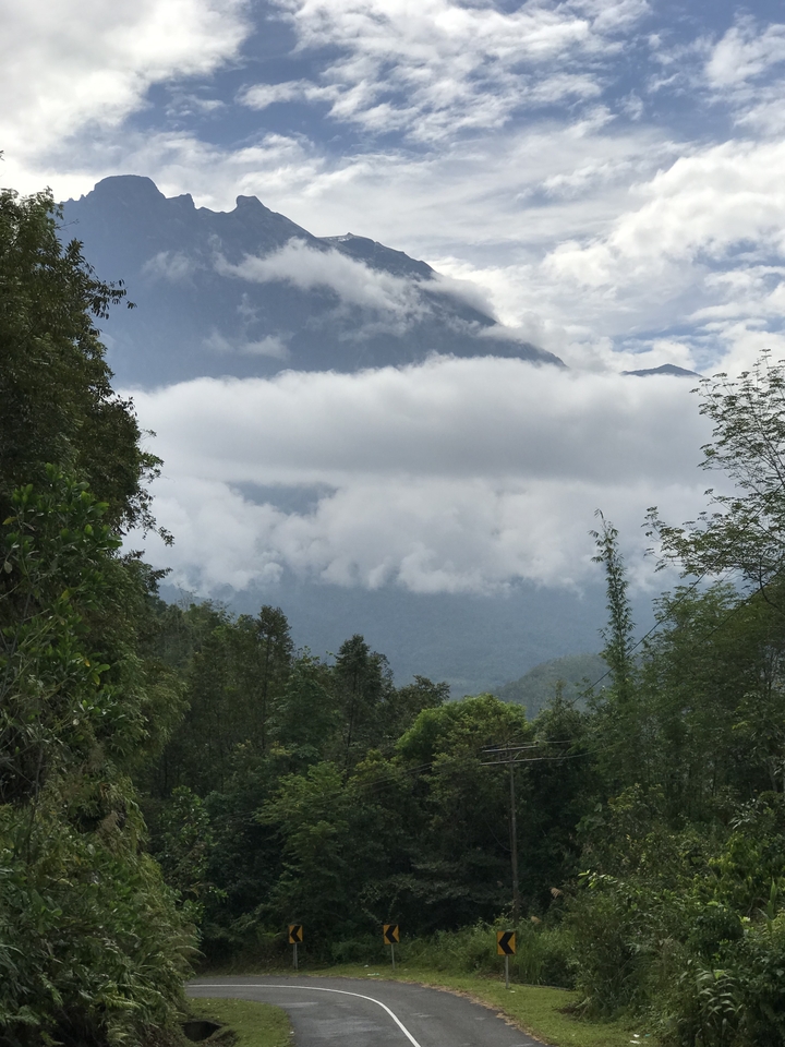 Cloud-covered mountains with dense forest in the foreground.