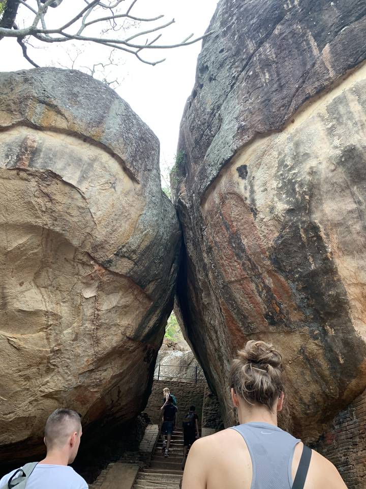 Tourists walking through narrow rock passage.