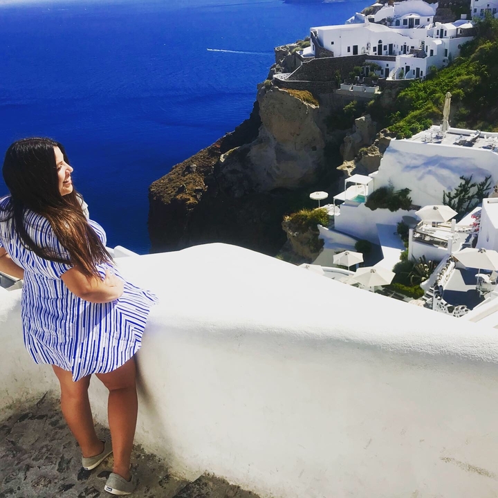 Une femme profitant d'une vue panoramique sur la mer avec des bâtiments blancs.