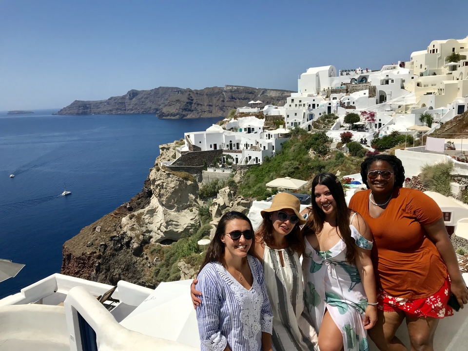 Groupe de femmes posant devant un magnifique paysage urbain côtier.