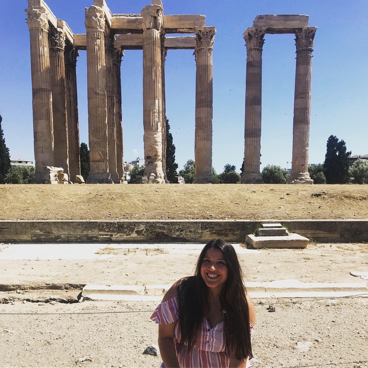 Une femme souriante devant des colonnes antiques.