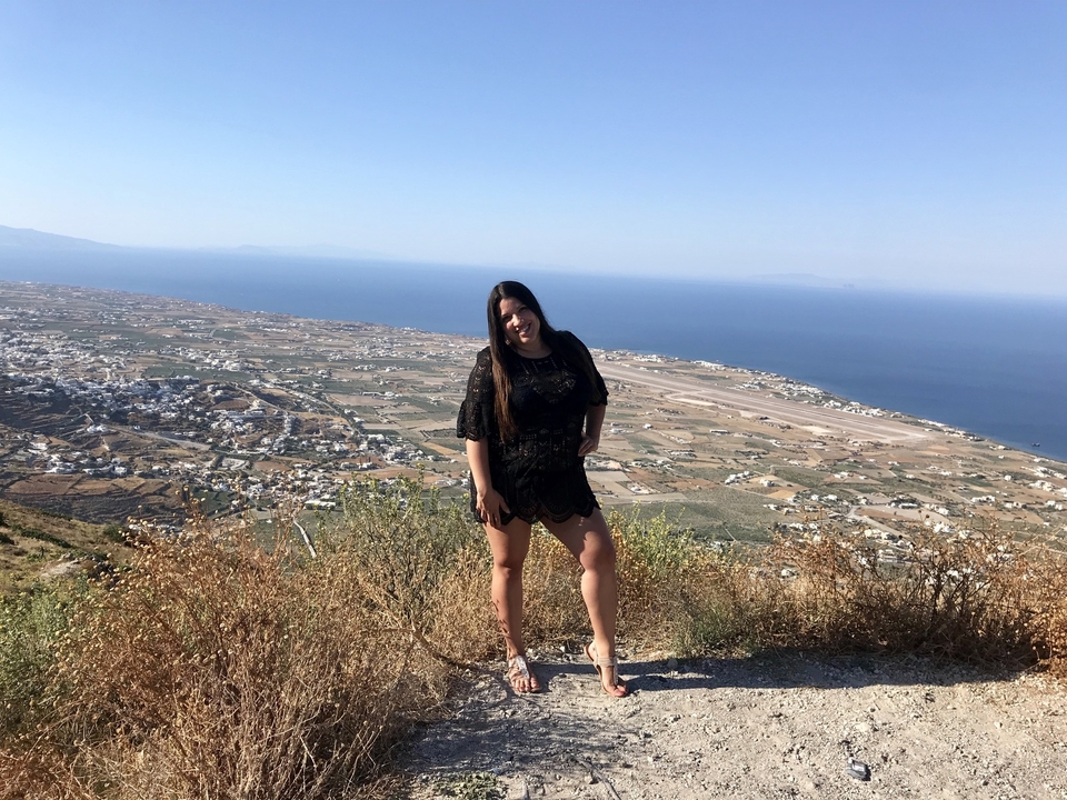 Une femme posant avec une vue aérienne d'une ville côtière.