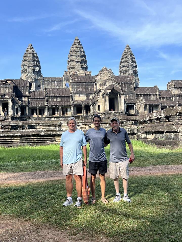 Trois personnes posant devant un grand temple.