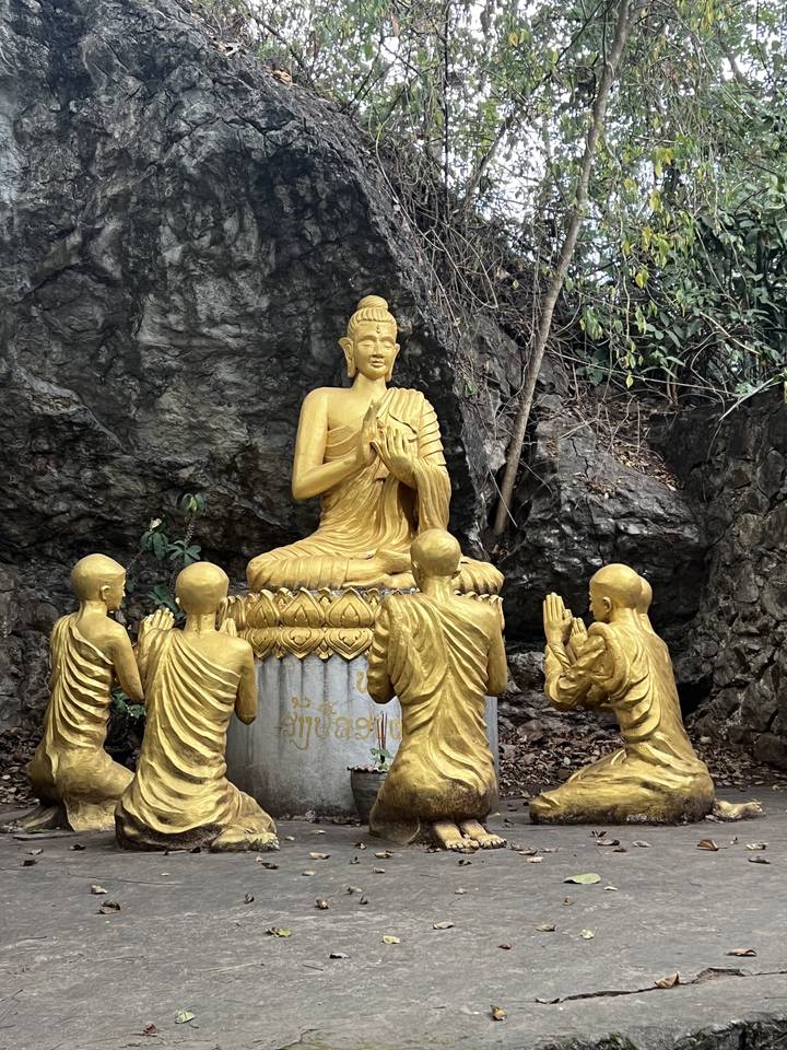 Statue de Bouddha dorée entourée de figures plus petites.
