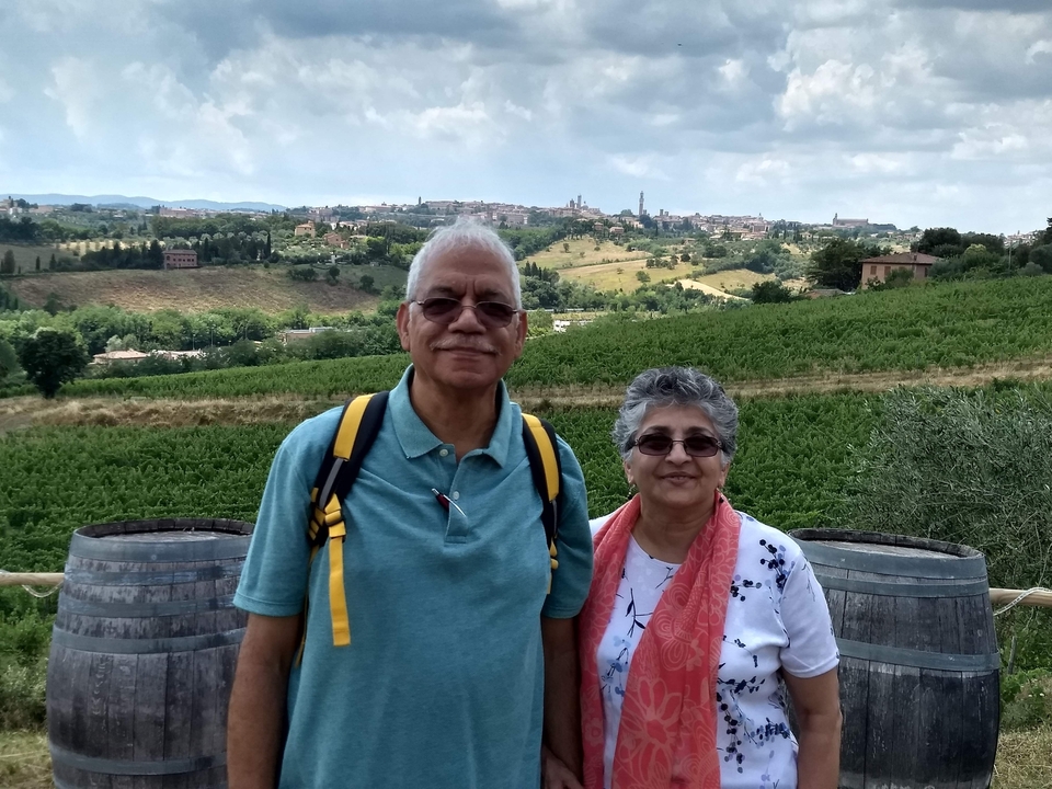 Couple posing in a vineyard with a hillside view.