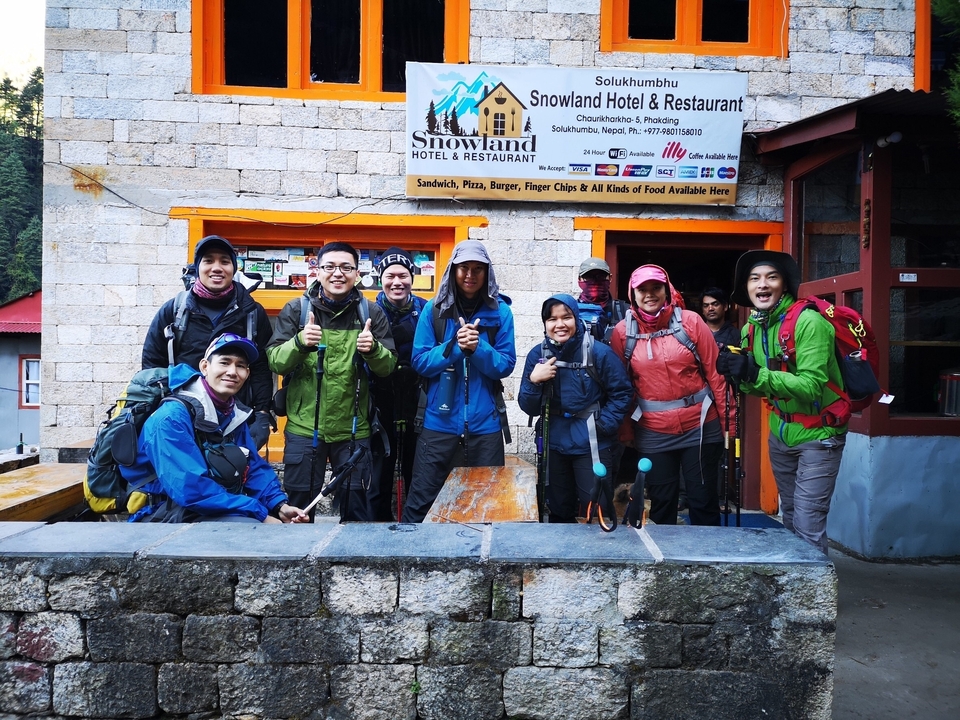 Groupe de randonneurs avec bâtons de marche posant devant un restaurant.