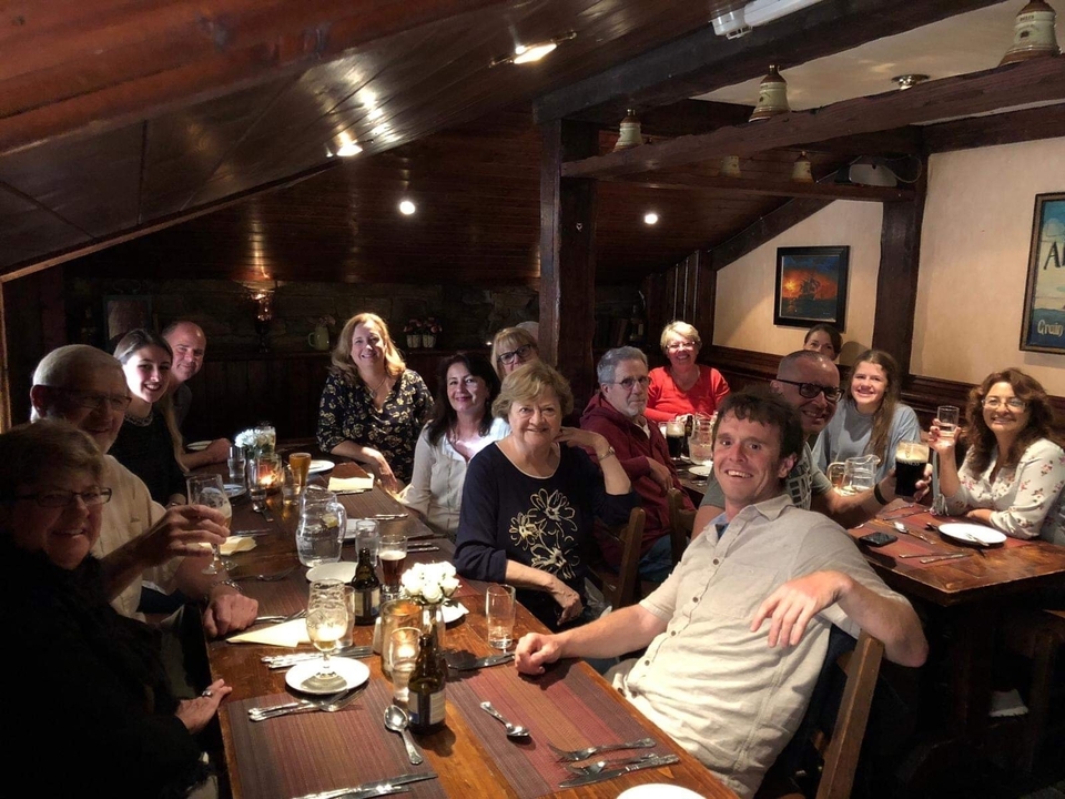 Groupe de personnes dînant à l'intérieur avec des boissons et des sourires.