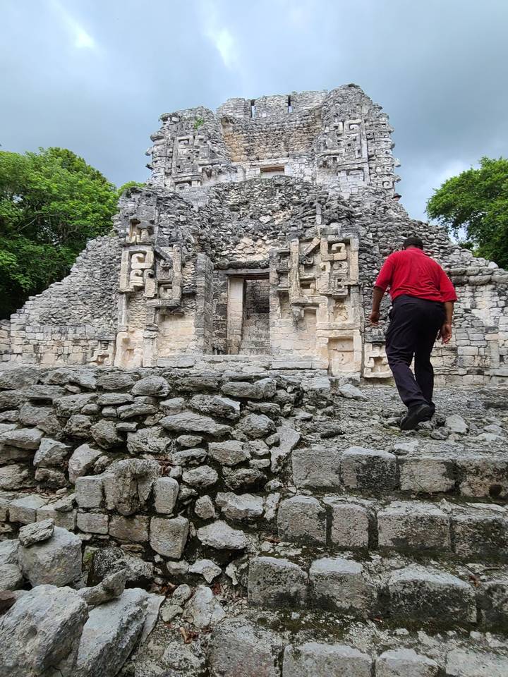 Person walking by ancient stone ruins with carved details.