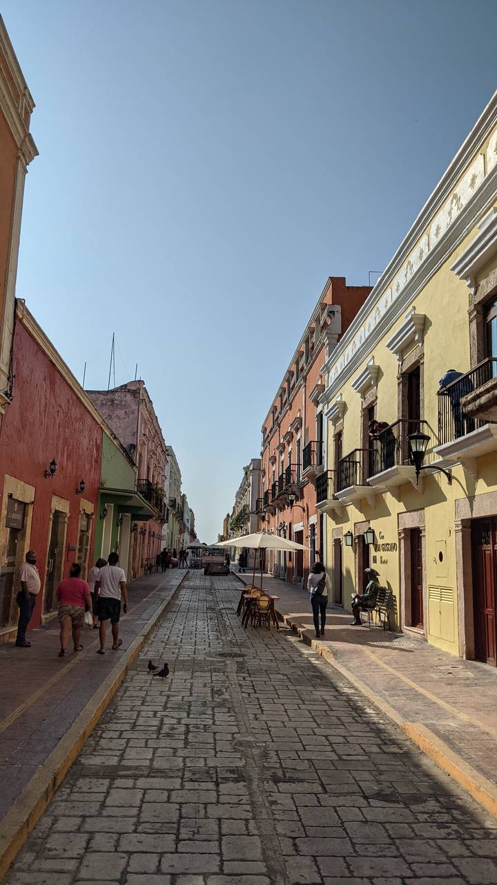 Colorful street scene with people walking and dining.