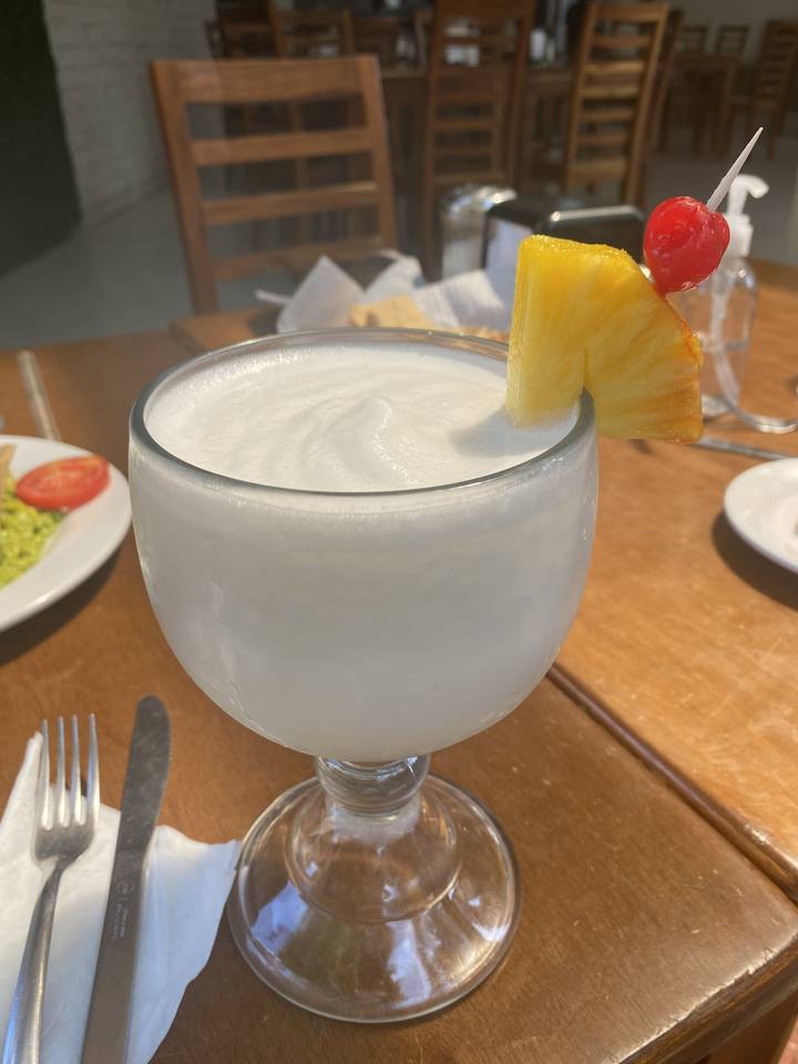 A cocktail drink on a table with chairs around.