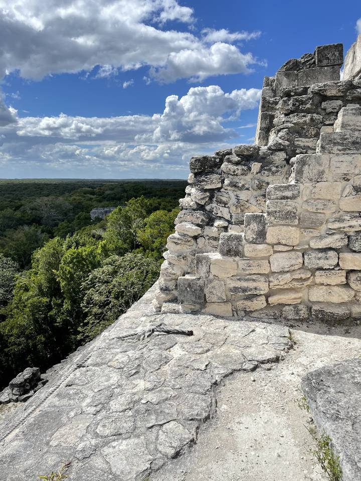 Stone wall with a view of the jungle and sky.