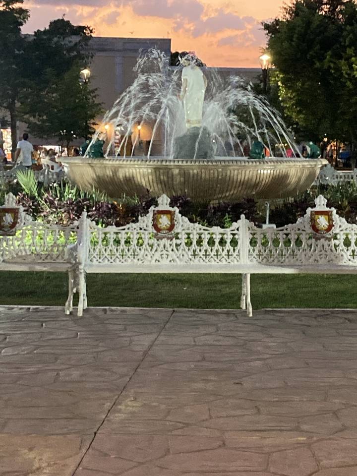 A fountain in a park during sunset.