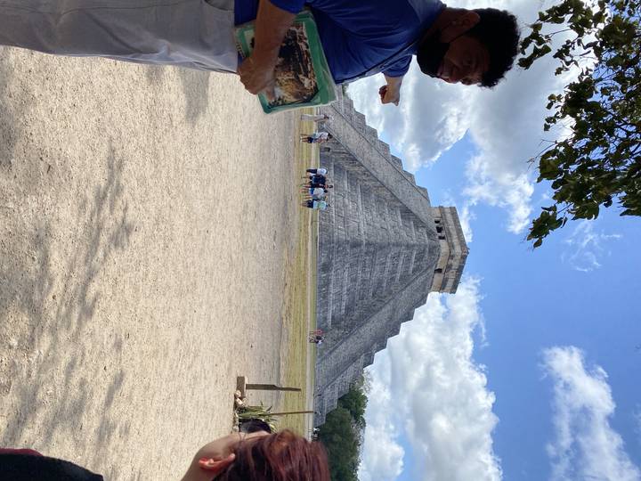 Tourists at the base of a large pyramid.