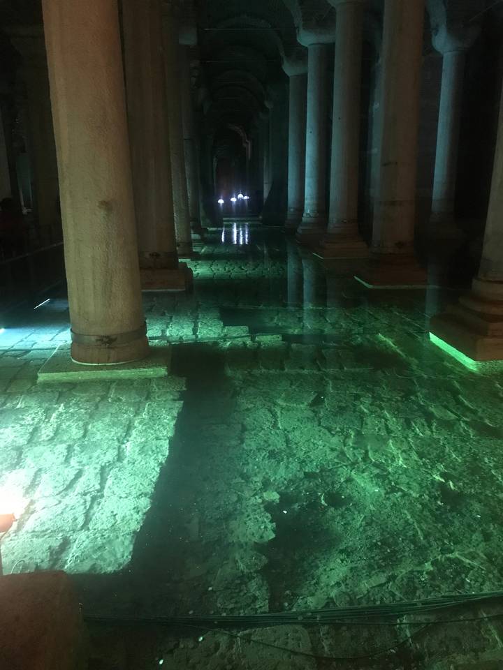 Subterranean columned walkway with green lighting.