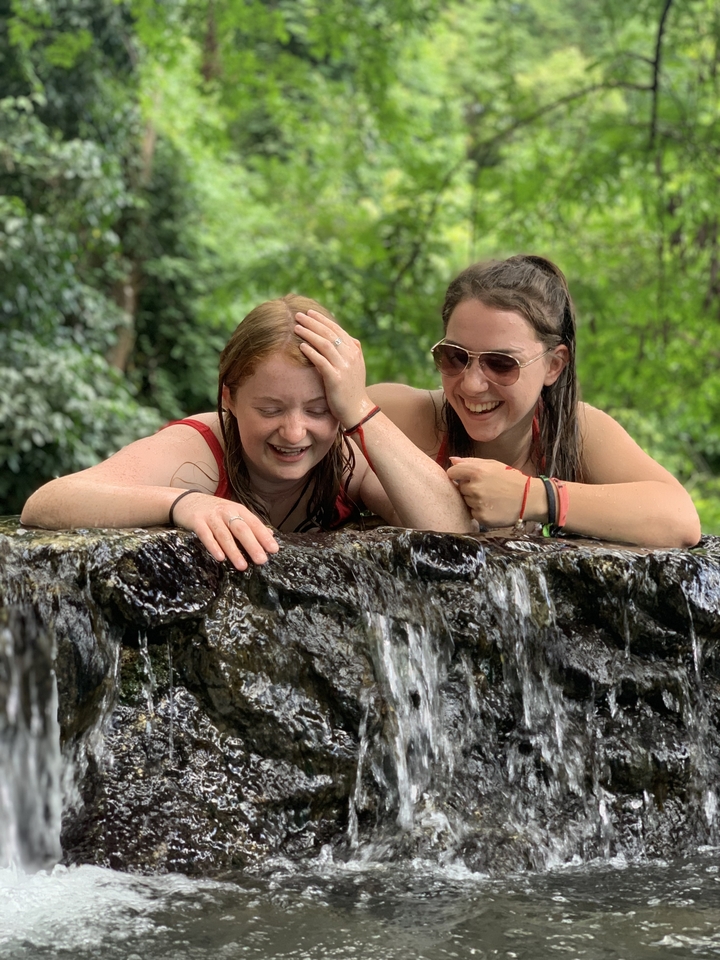 Two women laughing at a waterfall edge