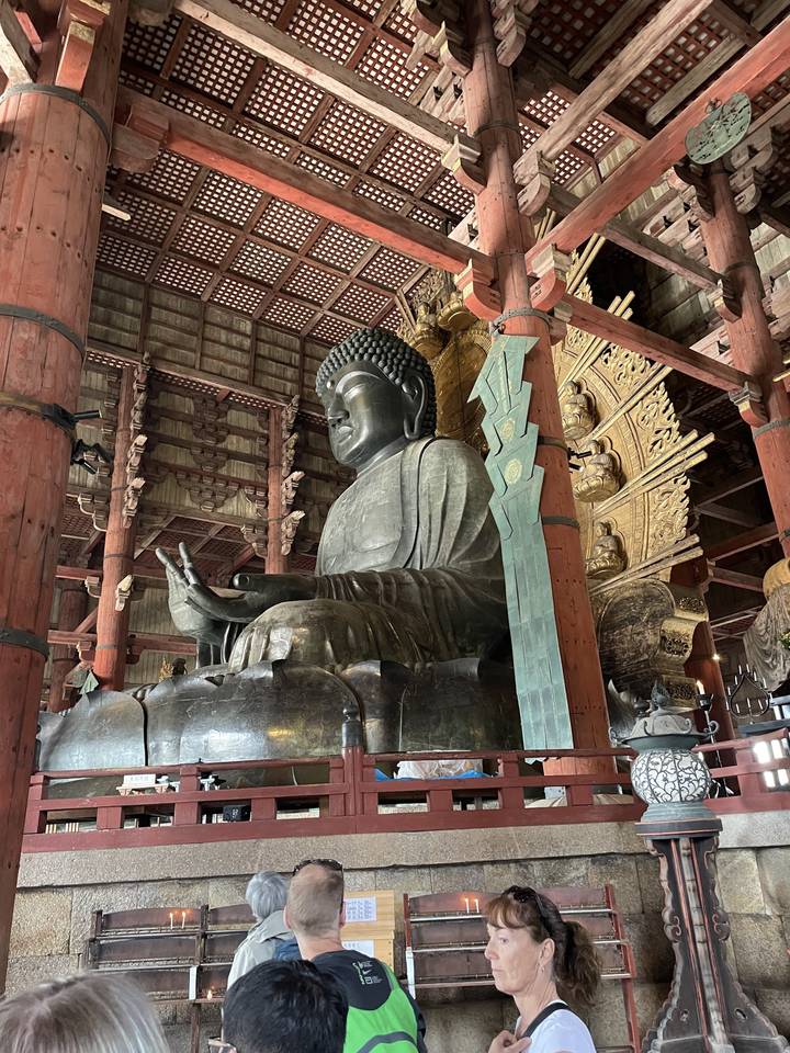 People viewing the Great Buddha statue inside a temple.