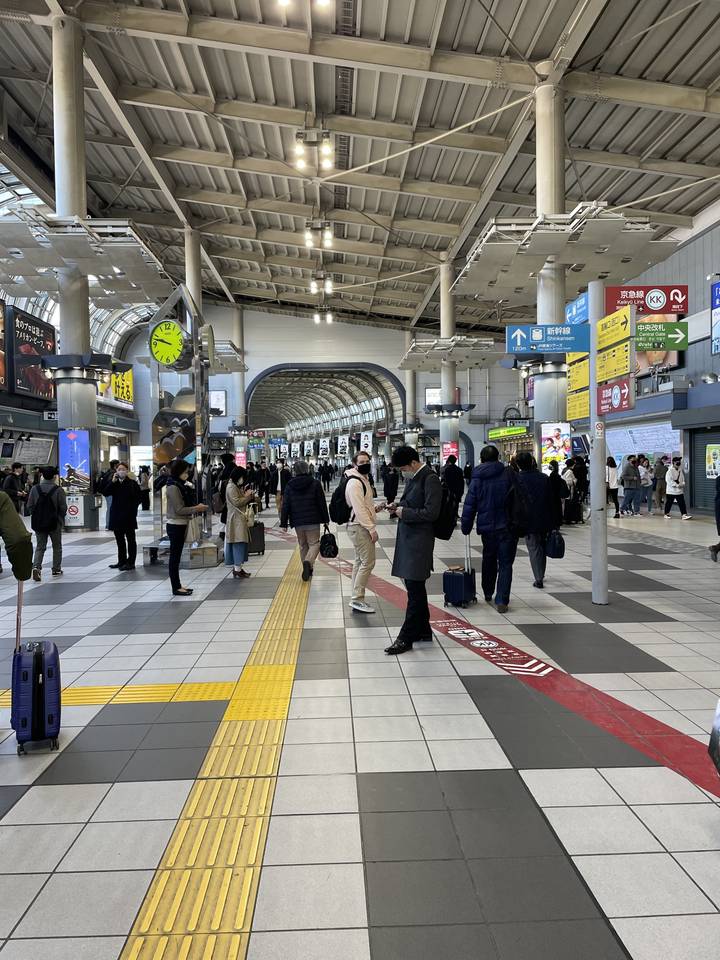People walking through a train station platform.