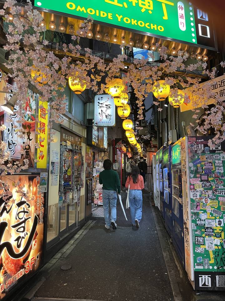 Rue étroite avec des lanternes et des boutiques, des gens qui marchent.