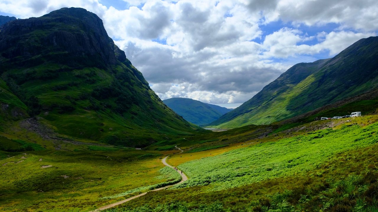Vibrant green valley under a cloudy sky.