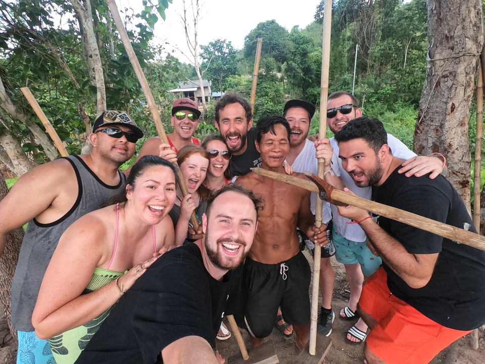 Group of people holding wooden staffs posing outdoors.