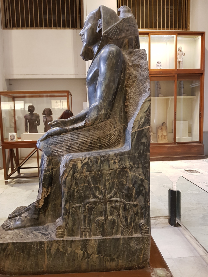 Statue of a pharaoh in a museum setting.