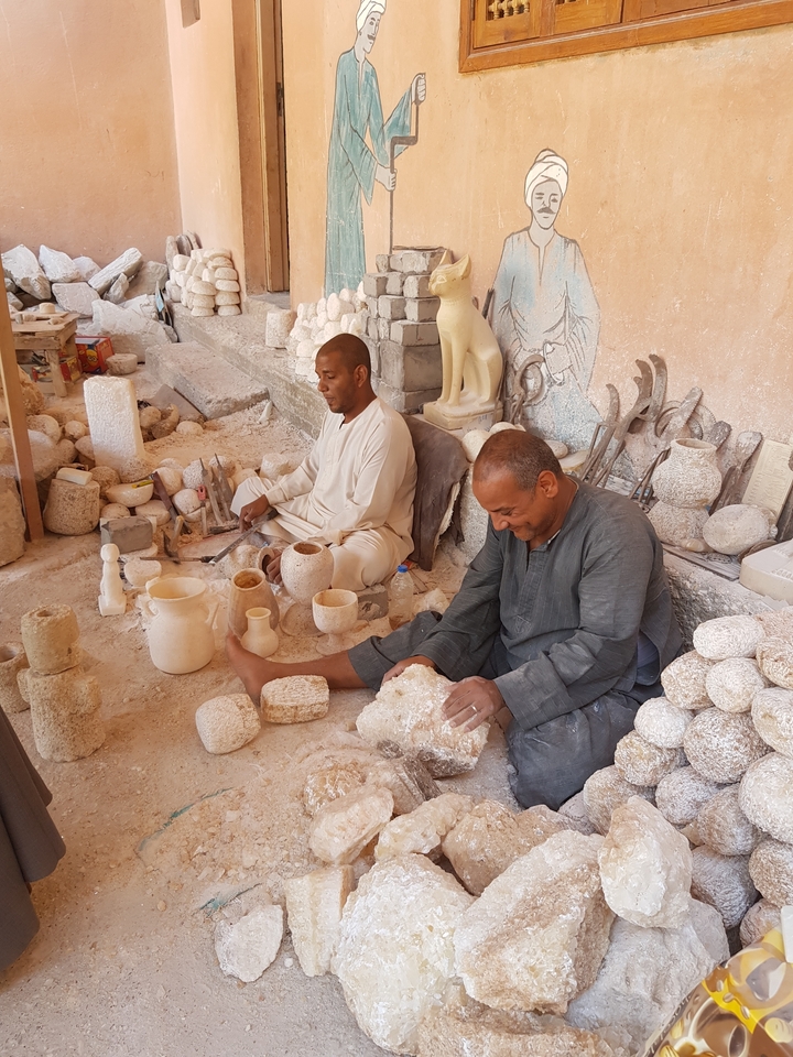 Craftsmen working with alabaster stone in a workshop.