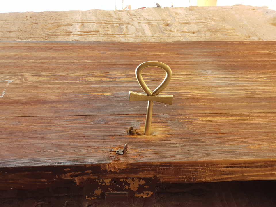 Large ankh key on a wooden table.