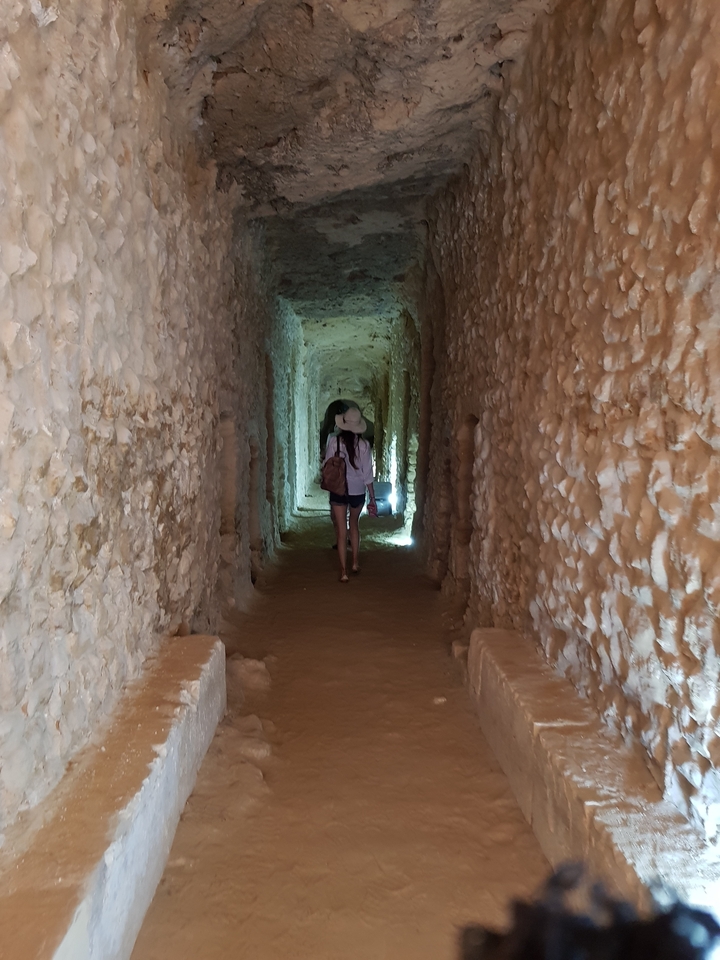 Person walking through a narrow, ancient tunnel.