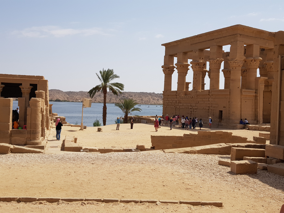 Temple ruins with a view of a lake and people around.