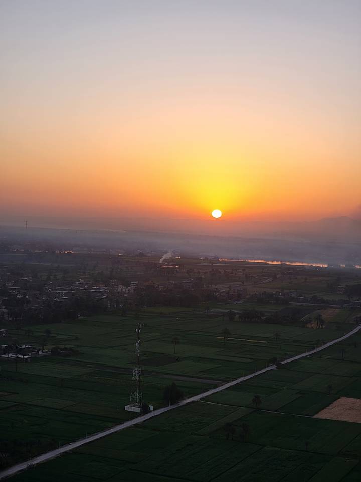 Sunrise over a lush valley with a river visible.