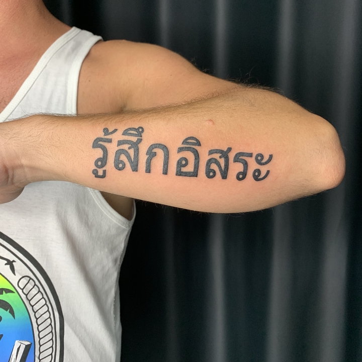Arm with a tattoo in Thai script.