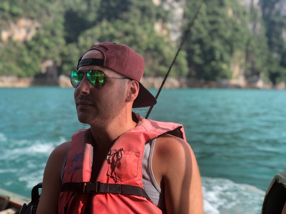 Man on a boat wearing sunglasses and life jacket.