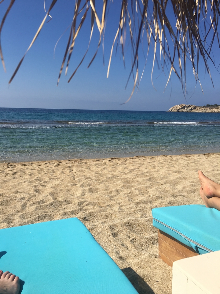 Sandy beach with calm waves and clear blue water.
