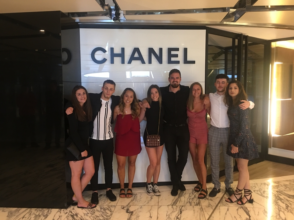 Groupe de personnes posant devant un magasin Chanel.
