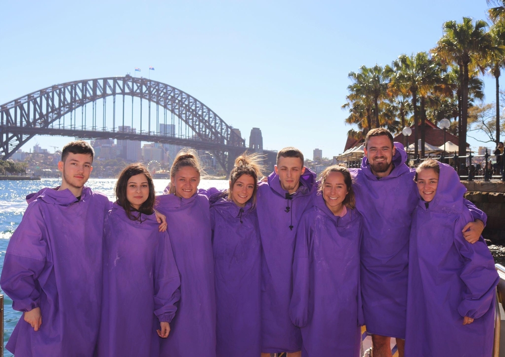 Groupe de personnes portant des ponchos avec le pont du port de Sydney en arrière-plan.