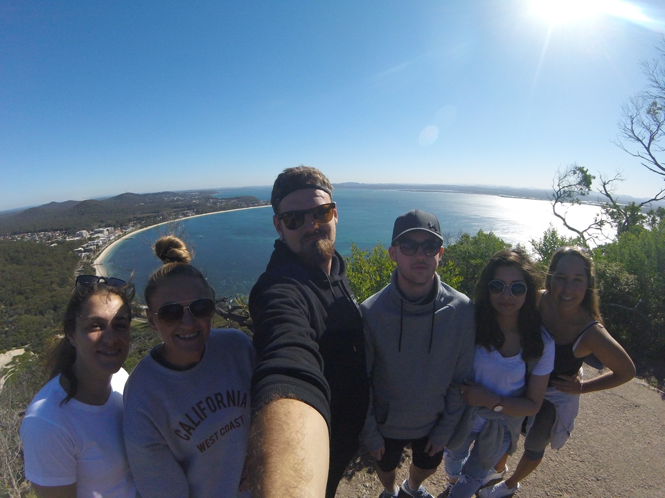 Selfie de groupe avec une vue côtière en arrière-plan.