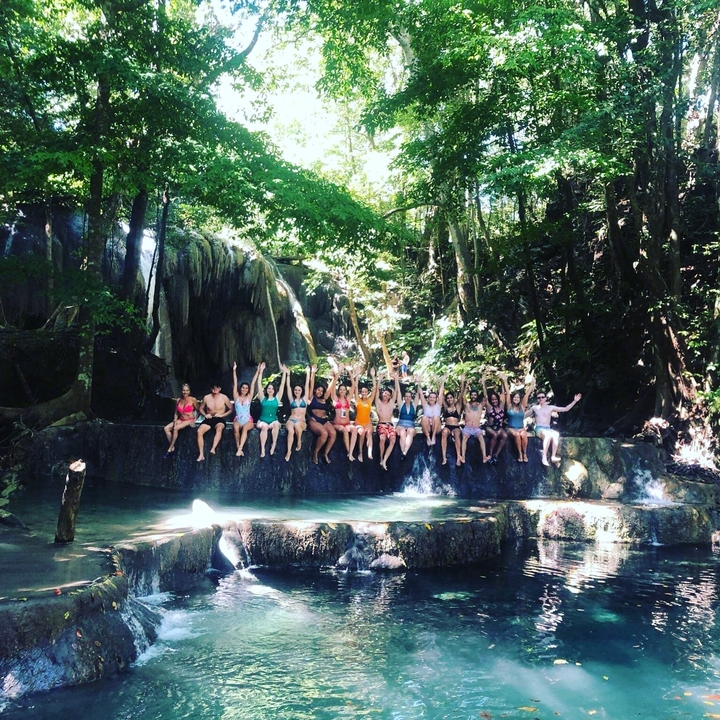 Group of people sitting at the edge of a waterfall.