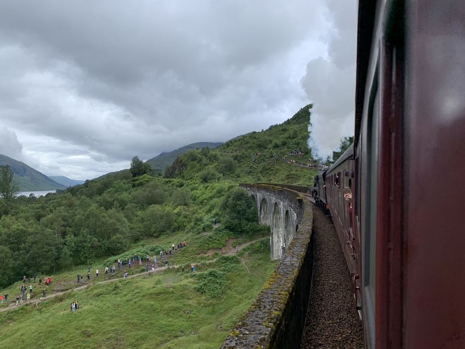 A steam train crosses a picturesque viaduct.