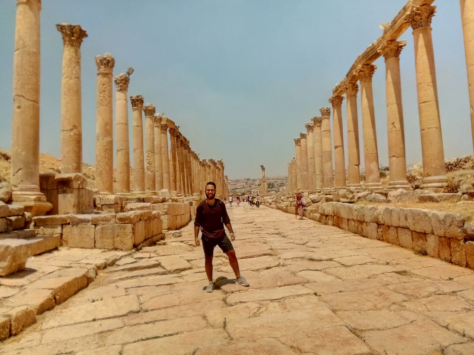 Person standing among ancient ruins with columns.